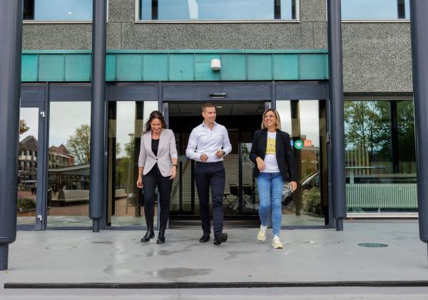 Collega's stappen lachend gemeentehuis uit